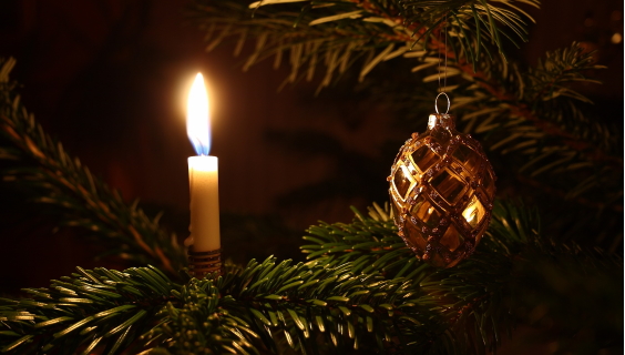 Gylden julekugle og levende lys på grangren